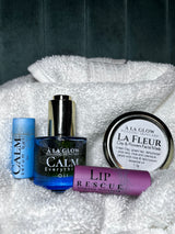 Set of skincare products including 'Calm' serum, oil, and lip rescue on a textured white surface.